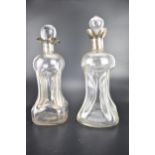 Two late 19th/early 20th century clear glass glug glug decanters, each with a silver four spouted