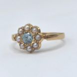 An 18ct gold aquamarine and seed pearl daisy ring, central aquamarine approx 3.7mm, size K, 2g