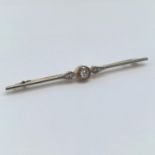 A 15ct white and yellow gold bar brooch having a central diamond, flanked by inset diamond