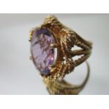 A gold coloured metal ring set with an amethyst in a claw and rope style setting, stamped Karba,