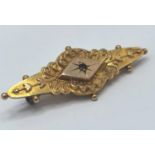 An Edwardian 9ct gold embossed brooch inset with a single ruby, 2.4g