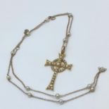 A 15ct gold seed pearl inset drop pendant in the shape of a Celtic cross, on a 9ct gold and pearl