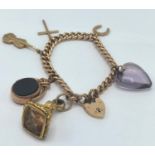A 15ct rose gold curb link charm bracelet having a 15ct gold heart shaped locket, 9ct charms to
