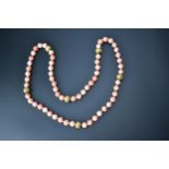 A coral necklace with 10mm polished pink beads and six silt metal decorative beads at intervals,