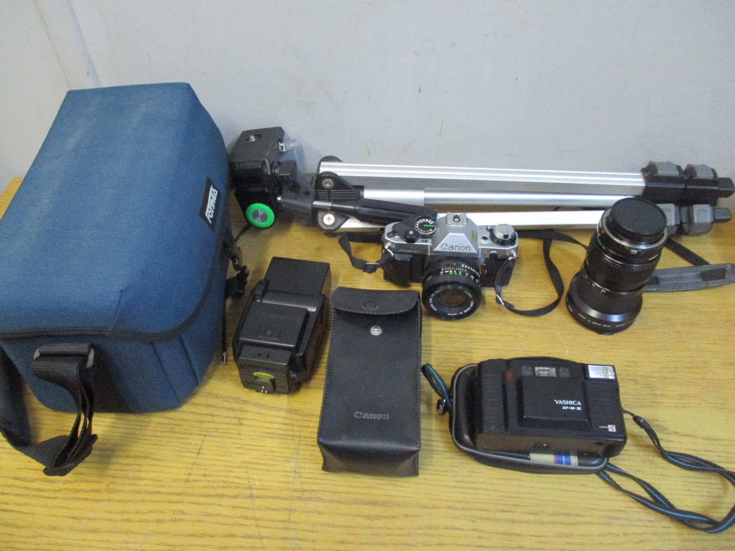 A Canon AE-1 camera, together with extra lens, fashion, tripod stand and a Yashica camera