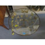 A circular topped coffee table, gilt metal frame with trailing leaf decoration, and inset glass top,