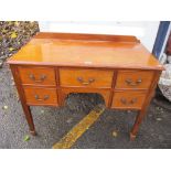 An early 20th century mahogany desk having five drawers, raised back and on square, tapering legs,