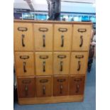 A mid 20th century light oak haberdashery/filing chest of twelve drawers with label holders and