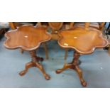 A pair of reproduction wine tables with tops in the shape of a flower above a tripod pedestal base