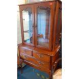 A reproduction American walnut glazed cabinet above two short and one long drawer on front