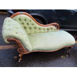 A Victorian walnut chaise longue having a carved, pierced frame, button back upholstery and short