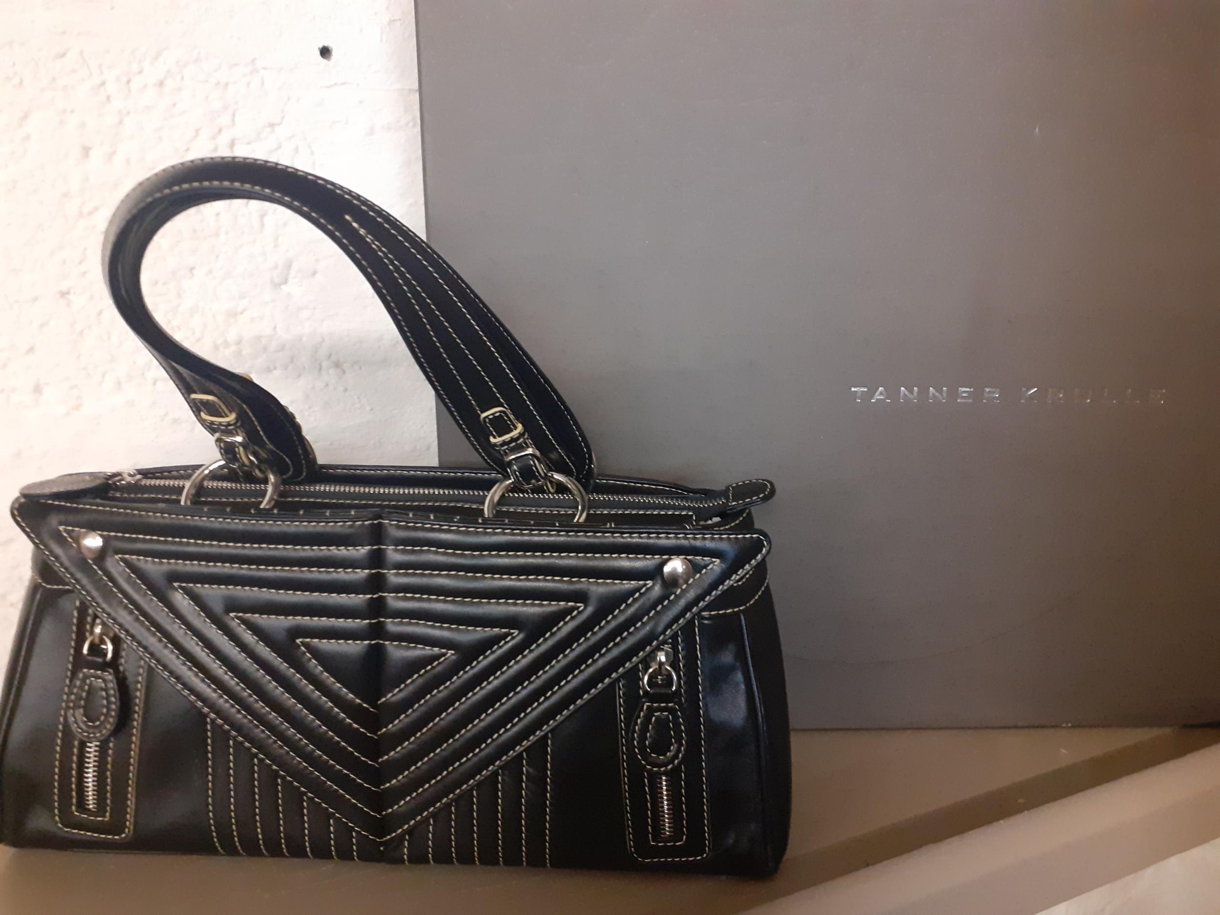 A Tanner Krolle black leather handbag with white stitching in a geometric fashion having silver tone