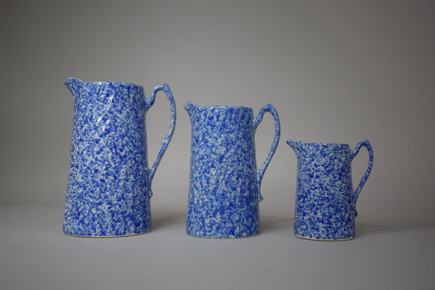 A Graduated Set of Three Glazed Mottled Blue and White Jugs, Tallest 20cm high