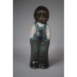 An Irish Glazed Stoneware Figure of a Child in Dungarees, 29.5cm high