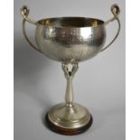 An Arts and Crafts Hammered Pewter Two Handled Trophy on Circular Wooden Plinth, 20cm high