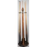 An Edwardian Country House Wooden Cue Stand Complete with Four Cues and a Rest, on Hexagonal Base,