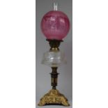 A Late Victorian Cast Iron Based Oil Lamp with Glass Reservoir and Acid Etched Cranberry Shade,