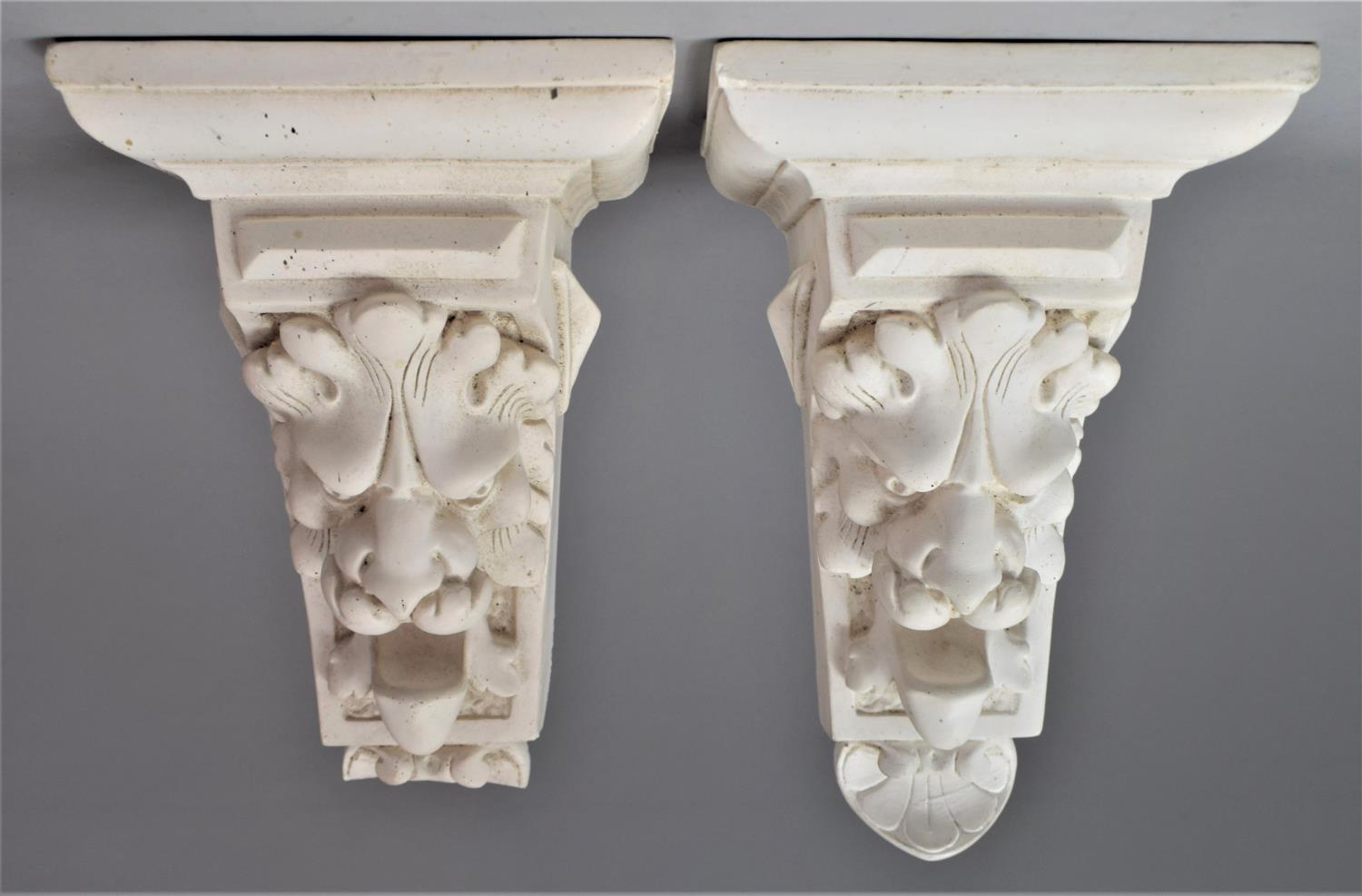 A Pair of Moulded Plaster Wall Hanging Lion Mask Shelf Sconces, 26cm high, One with Loss to Base