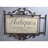 A Vintage Wrought Iron Framed Wall Mounting Shop Sign with Painted Wooden Board, "Antiques,