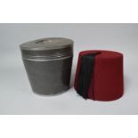A Modern North African Fez in Tin Container, 19cm Diameter