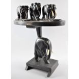 A Carved Wooden Oval Topped Table with Elephant Support and Three Ebonised Elephant Figures