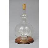 A Contemporary Glass Ship in a Bottle on Circular Wooden Plinth, 28cm high