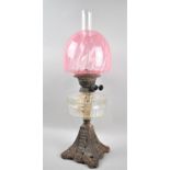 A Late Victorian Iron Based Oil Lamp with Clear Glass Reservoir and Cranberry Glass Shade, Overall