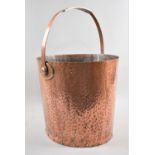 A Hand Beaten and Riveted Copper Bucket with Loop Handle of Oval Form, 28cms Long and 25cms High