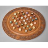 A Carved Circular Solitaire Board and Collection of Polished Stone Specimen Marbles with Paper