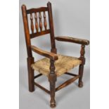 A 19th Century Child's Arm Chair with Turned Spindle Back Over a Rushed Seat Supported on Turned