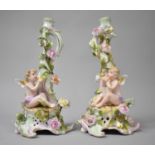 A Pair of Schierholz Porcelain Figural Candlesticks both Set with Seated Cherubs Eating Fruit.