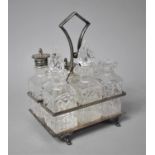 An Edwardian Silver Plate and Glass Six Bottle Cruet, the Rectangular Tray on Four Scrolled Feet,