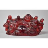 A Chinese Red Resin Figure Group of Smiling Buddhi with Children, 20cm wide and 9.5cm high