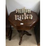 A VINTAGE WOODEN MAHOGANY GAMES TABLE WITH COMPARTMENT FOR CHESS PIECES WHICH ARE MADE FROM