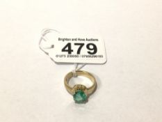 A YELLOW METAL AND EMERALD SOLITAIRE RING, NIBBLES TO THE EDGE OF THE STONE, PRESUMED TREATED, SET