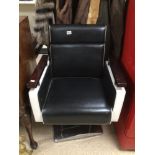 A BLACK AND WHITE BARBERS CHAIR ON CHROME ADJUSTABLE BASE