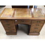 AN ANTIQUE LEATHER TOP WRITING DESK WITH FOUR DRAWERS EITHER SIDE AND CENTRAL DRAWER