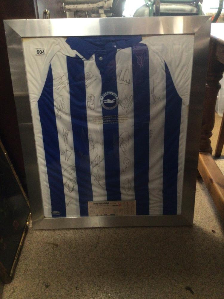 A FRAMED AND GLAZED BRIGHTON AND HOVE ALBION SIGNED FOOTBALL SHIRT FROM THE FIRST GAME AT THE AMEX