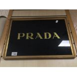 A VINTAGE FRAMED AND GLAZED PRADA SIGN 51 X 36CM