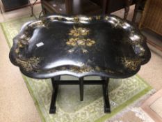 AN EBONISED PAPIER MACHE FOLDING TRAY WITH DECORATIVE TOP GILDED AND INLAID MOTHER IN PEARL