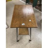 AN OAK TWO TIER TABLE ON CASTORS WITH METAL LEGS