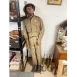 VINTAGE MALE MANNEQUIN DRESSED IN ARMY UNIFORM AND BOOTS WEARING A BRODIE STYLE HELMET