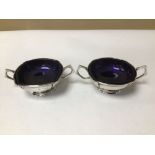 A PAIR OF EDWARDIAN HALLMARKED SILVER TWIN HANDLE SQUARE SALTS WITH ORIGINAL BLUE LINERS 1905 BY