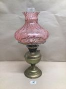 A VINTAGE BRASS OIL LAMP WITH A PINK-TINTED GLASS SHADE, BEING 48CM IN HEIGHT