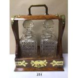 AN OAK AND BRASS ANTIQUE TANTALUS FITTED WITH TWO DECANTERS (NO KEY)