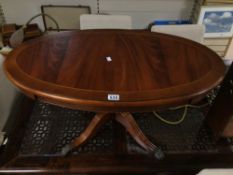 FLAME MAHOGANY OVAL COFFEE TABLE ON A PEDESTAL BASE WITH BRASS CLAWS