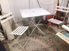 A WHITE METAL FOLDING GARDEN TABLE WITH TWO METAL FOLDING CHAIRS