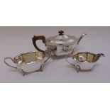 A silver three piece teaset, elongated octagonal on four scroll legs, Sheffield 1938 the cream jug