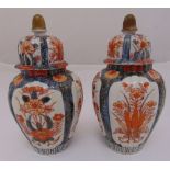 A pair of Imari baluster vases with domed pull off covers decorated with flowers and leaves, 22cm (