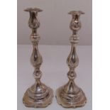 A pair of silver table candlesticks of knopped baluster form, chased with floral swags on shaped